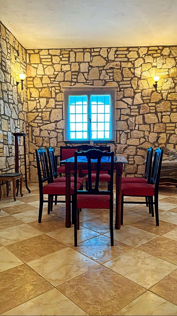 Πέτρινη αίθουσα του κτήματος με τραπέζι και καρέκλες